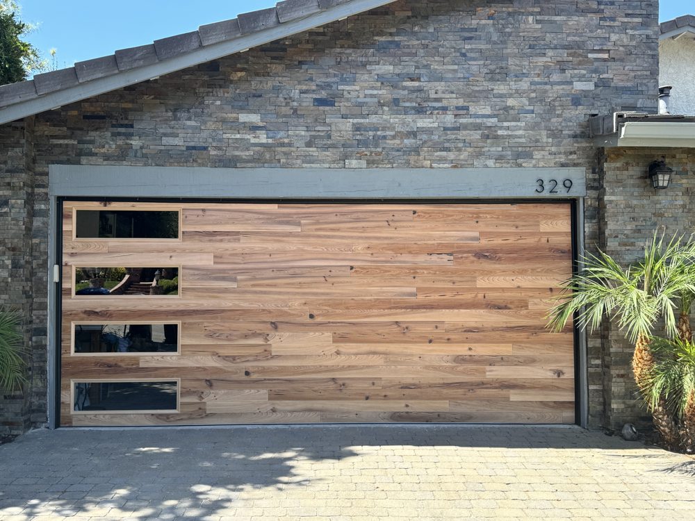Modern wooden garage door with stone wall and plants in view
